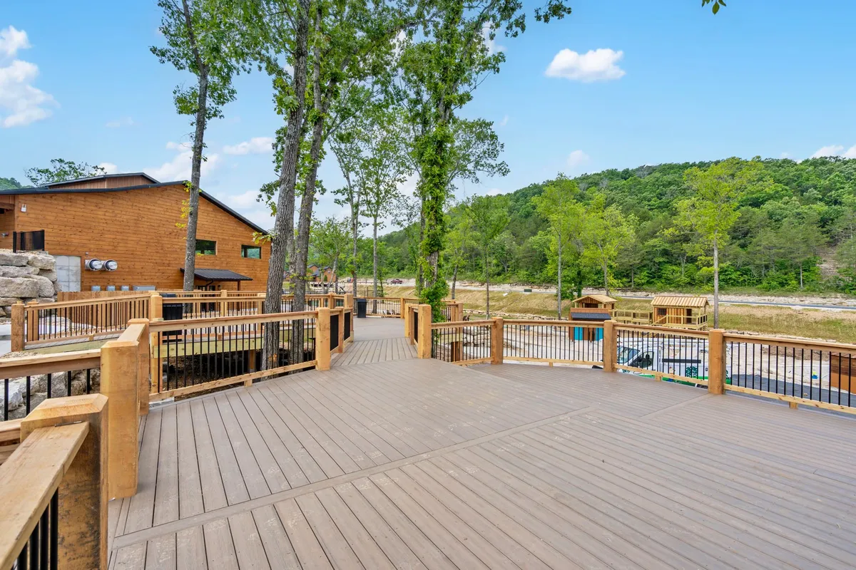A wooden deck with outdoor seating, offering panoramic views of the surrounding trees and distant mountains. The space feels open and tranquil, ideal for unwinding while soaking in nature.