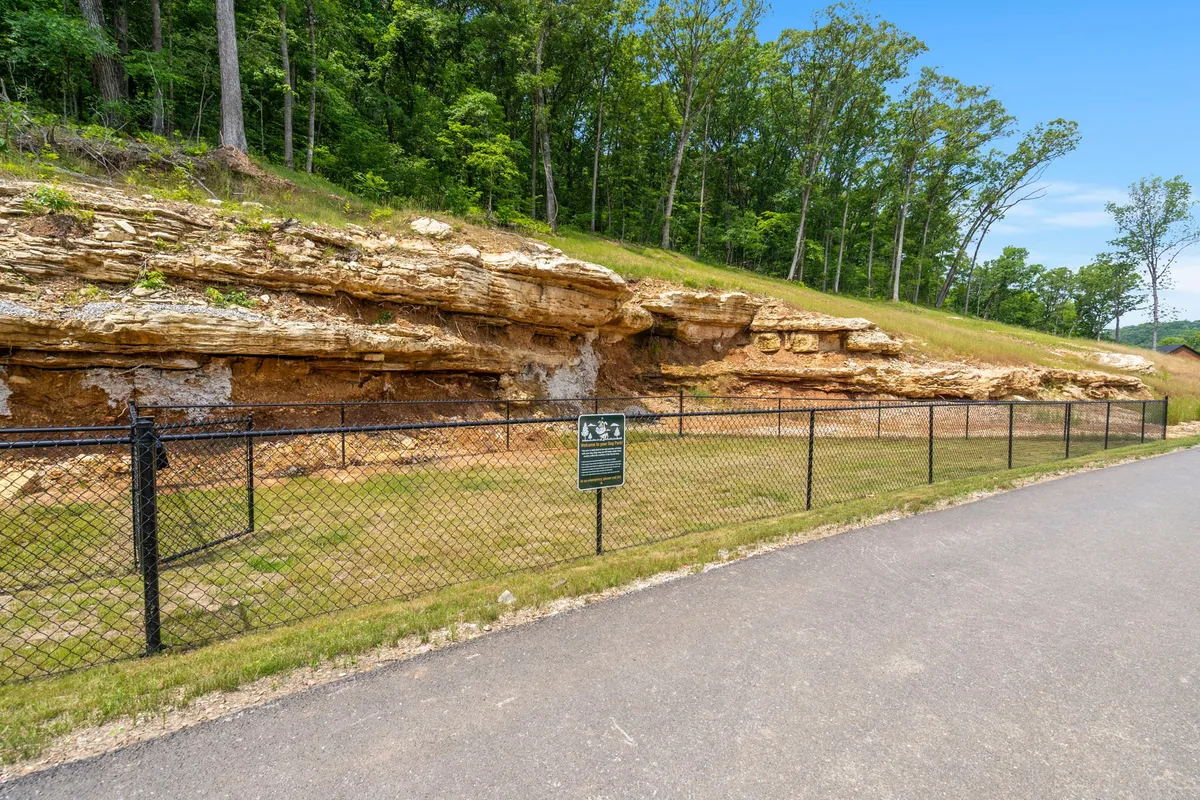 An outdoor scene featuring unique rock formations, a fenced pathway, and an informational sign, inviting exploration and educational nature walks in the Ozarks’ scenic landscape.